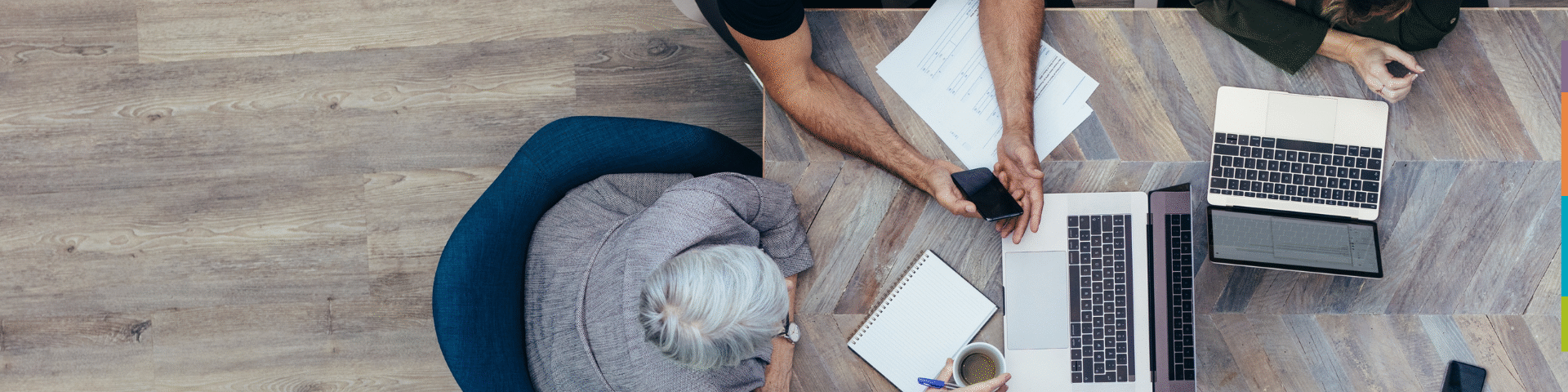 Aerial view of three professionals collaborating at a table, symbolising strategic hiring and executive search partnerships